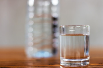 Drinking water in glass and plastic bottles on a wooden table.