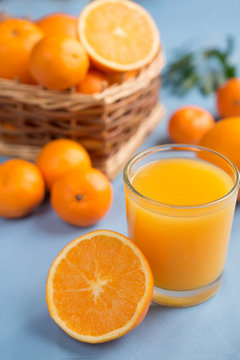Fresh orange juice in a glass on a background of fruit baskets