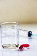Pills and syringes for treating patients on a white background.