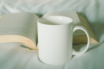 White cup with book on bed