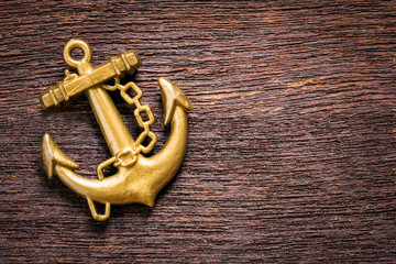 Golden anchor on grunge wood background © pachaileknettip
