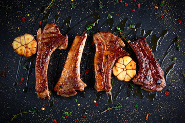 Roasted lamb cutlets ribs with garlic and herbs on stone background