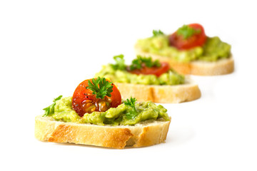 avocado cream or guacamole and tomatoes on baguette canapes isolated on white