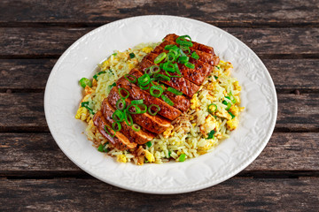 Chinese style Egg fried rice with sliced pork fillet on wooden table.