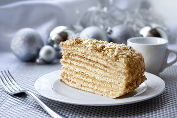 Piece of layer cake on a plate with Christmas balls on the background