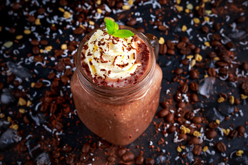 Coconut coffee chocolate smoothie with whipped cream on decorated table.