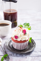 Dessert for Valentines Day, beautiful red velvet cupcake decorated with pink rose on old white wooden background with copy space.
