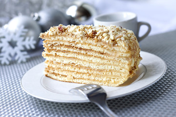 Piece of layer cake on a plate with Christmas balls on the background