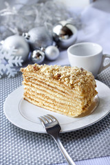 Piece of layer cake on a plate with Christmas balls on the background
