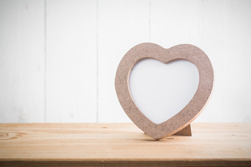 Heart shaped photo frame on wood table