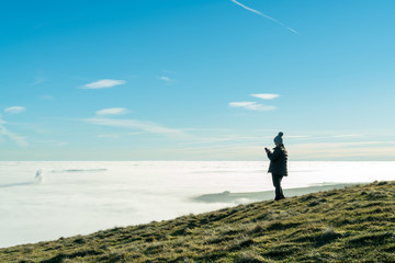 A female hiker takes a photo of the misty morning view in the Hope Valley. Mam Tor, Peak District