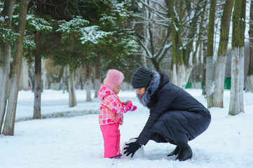 Fototapeta na wymiar Little girl and her mom playing in the snow