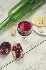 pomegranate, wine and  cheese on the table