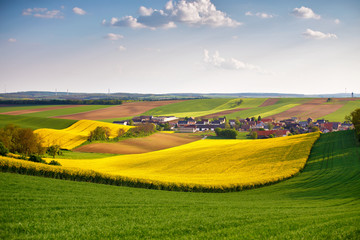 Fototapeta premium Austria spring colza fields. Village on a hills.