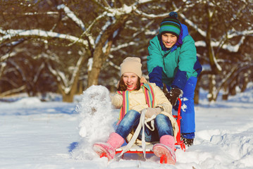Happy boy and girl sledding in winter outdoor