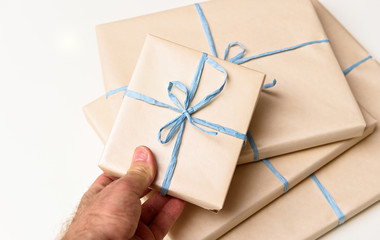 Man holding gift wrapped in luxury paper with organic blue rope