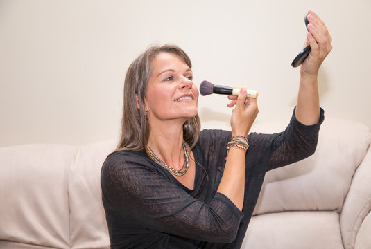 Middle aged woman applying make-up.