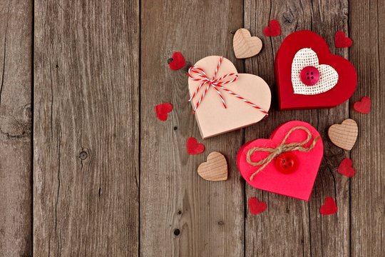 Valentines Day heart shaped gift boxes with red and burlap trim in a cluster over wood