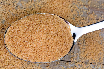 Spoon with beige sugar on table