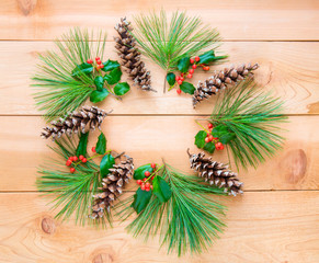 Pine cones and branches with holly berry in form of Christmas wr