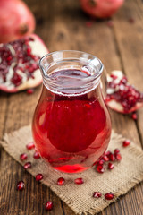 Portion of Pomegranate juice on wooden background (selective foc
