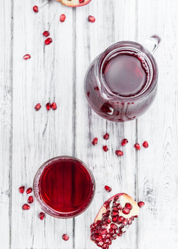 Portion of Pomegranate juice on wooden background (selective foc