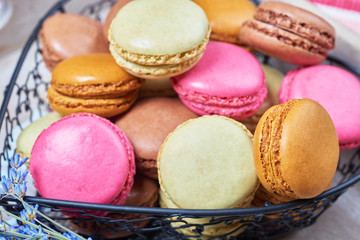 Colorful french macaroons in a heart shaped basket