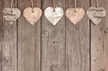 Rustic birch bark heart ornaments hanging against a vintage wooden background - Powered by Adobe