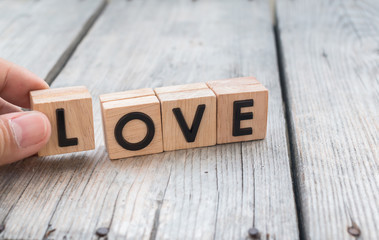 Man hold words "Love" from wooden cubes on wood table , people,