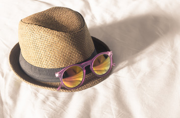 Brown hat with pink sunglasses on bed