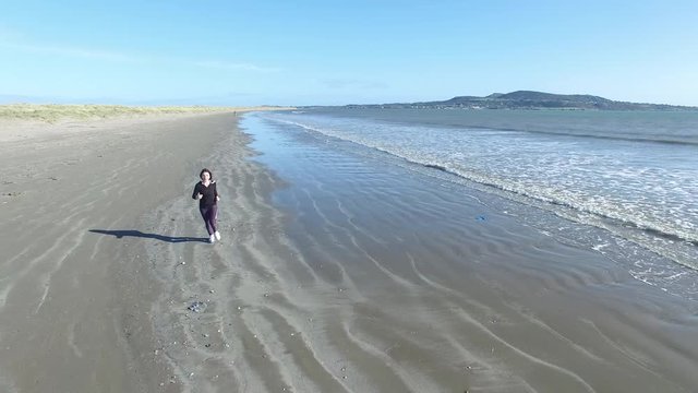 4k aerial video of a woman running on the beach