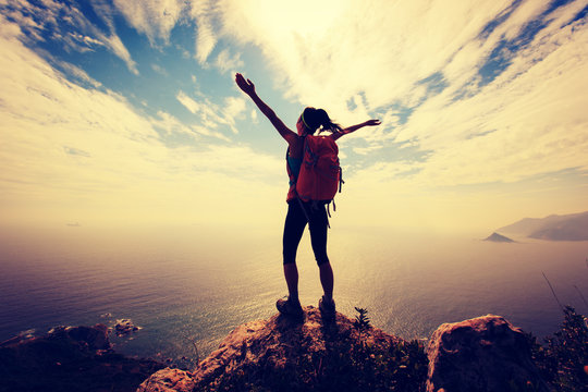 successful woman backpacker hiking on mountain peak
