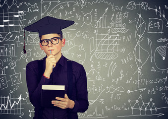 Man in graduation cap with book thinking about education