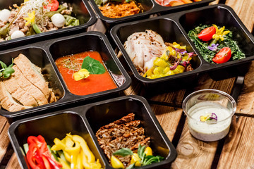 Healthy food and diet concept, restaurant dish delivery. Take away of fitness meal. Weight loss nutrition in foil boxes. Steamed veal with cous and vegetables at wood