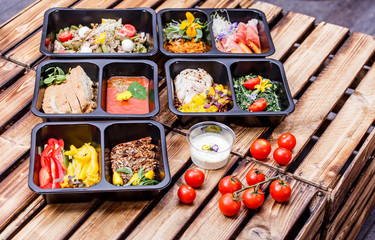 Healthy food and diet concept, restaurant dish delivery. Take away of fitness meal. Weight loss nutrition in foil boxes. Steamed veal with cous and vegetables at wood