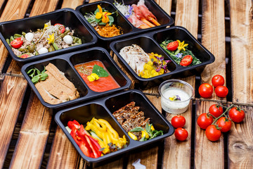 Healthy food and diet concept, restaurant dish delivery. Take away of fitness meal. Weight loss nutrition in foil boxes. Steamed veal with cous and vegetables at wood