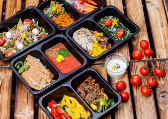 Healthy food and diet concept, restaurant dish delivery. Take away of fitness meal. Weight loss nutrition in foil boxes. Steamed veal with cous and vegetables at wood