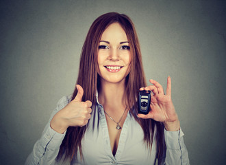 Happy woman showing remote car keys and thumbs up