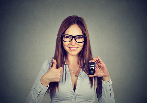 Happy woman showing remote car keys and thumbs up