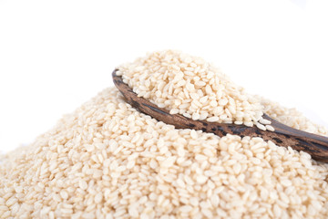 Wooden spoon with sesame seeds on a white background