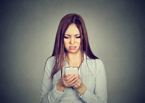 Upset woman looking at cellphone displeased with message she received