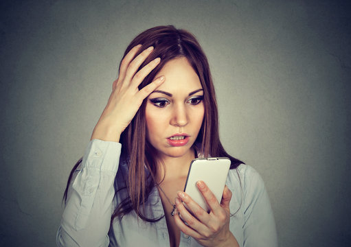 Upset woman looking at cellphone worried with message she received