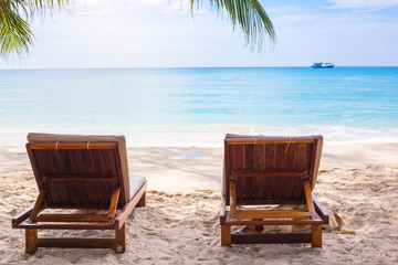 Beach chairs on the white sand beach with  blue sky and sun