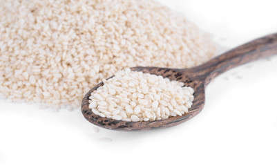 Wooden spoon with sesame seeds on a white background