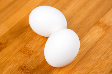 Whole white eggs isolated on a wood background