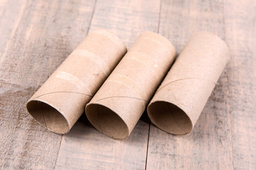 Three empty toilet paper rolls isolated on a wood background