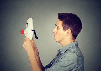 Sad man putting on happy mask