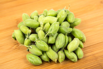 Fresh raw garbanzo beans in the pod isolated on a wood background