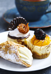 Small pastries. Sicilian cannoli, mango cheesecake and classic cheesecake