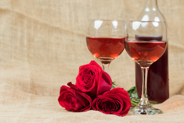 Two glasses of wine and roses on burlap
